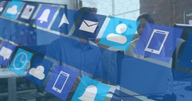 Modern ofis masasında işbirliği yapan iş arkadaşları, yüzen bilişim simgeleriyle dizüstü bilgisayar ekranlarını izliyorlar. Teknoloji, takım çalışması, yenilik, iletişim, dijital, çalışma alanı, işbirliği