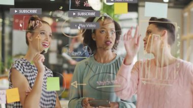 Üç bayan meslektaşım, cam panoda yüzen abonelik simgeleriyle pazarlama fikirleri üretiyor. İşbirliği, yenilik, takım çalışması, yaratıcılık, beyin fırtınası, dijital iletişim, modern ofis