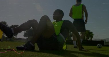 Erkek futbolcular çim sahada antrenman yapıyor ve animasyon finans tabloları sahada yüzüyor. Atletik, takım çalışması, motivasyon, açık hava, spor kıyafeti, canlı.