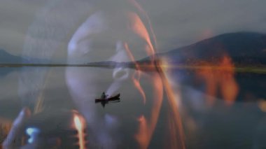 Yolculuk sahnesinde, alacakaranlıkta dağ gölünde sıcak alevleri harmanlayan bir adam kürek çekiyor. Macera, sükunet, manzara, yansıma, gerçeküstü, alacakaranlık, vahşi doğa.