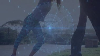 Ahşap terasta partner yogası yapan iki kadın fitness teknolojisinin rakamlarla üst üste bindiğini gösteriyor. Sağlık, zindelik, açık hava, yenilikçi, teknoloji, işbirliği, canlılık