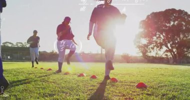 Takım gün batımında spor eğitimi için külahlarla ayak çalışması talimi yapıyor, veri grafiklerini örtüyor. Atletik, takım çalışması, eğitim, açık hava, canlı, kararlılık, rekabet