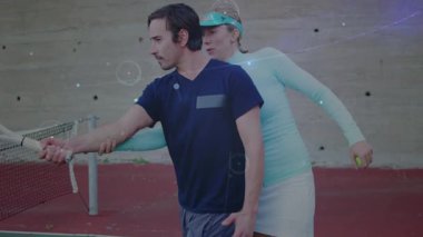 Tenis koçu rehber oyuncu net 'te sallanıyor, kırmızı kortta hareketli raket yolunu gösteriyor. Atletik, antrenman, antrenman, spor, aktivite, açık hava, enerjik
