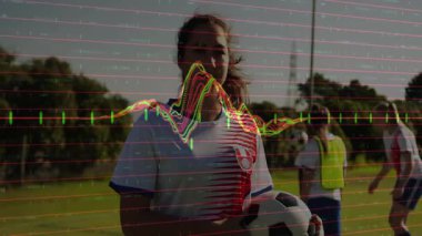 Genç kız futbol topunu sahada tutuyor, kırmızı çizgiler ve spor pazarlaması için dalga boyu gösteriyor. Atletik, takım çalışması, canlı, fitness, rekabet, açık hava, dinamik