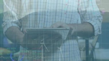 Modern ofiste tablet paylaşım finans tableti tutan adam rüzgar türbini simgelerini gösteriyor. Teknoloji, yenilik, sürdürülebilirlik, işbirliği, veri analizi, kurumsal, modern