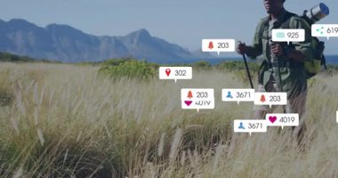 Dijital pazarlama için yüzen sosyal medya simgeleriyle altın çim tarlasında yürüyüş yapan yürüyüşçü. Macera, keşif, açık hava, doğa, bağlantı, teknoloji, yaşam tarzı