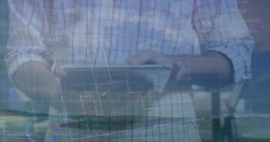 Adam pencerenin yanındaki dizüstü bilgisayarda yüzen finans çizelgeleri ve akıllı telefonuyla yazı yazıyor. Üretkenlik, teknoloji, veri görselleştirme, profesyonel, iş dünyası, yenilik, yaratıcı