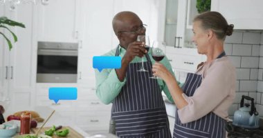 Mutfak ekibi, modern beyaz mutfakta, yüzen dijital sohbet baloncuklarıyla şarap kadehlerini tokuşturuyor. Yemek pişirme, kutlama, çağdaş, yerli, gurme, işbirliği, tarz