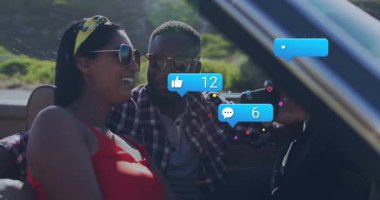 Çift arkaya yaslanıyor ve telefonu kullanıyor, arabada selfie çekiyor, sosyal medya simgeleri havada uçuşuyor. Yaşam tarzı, macera, neşeli, açık hava, modern, arkadaşlık, rahatlama