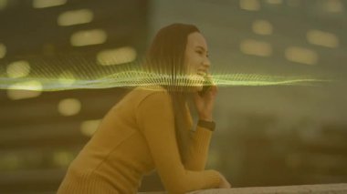 Kadın çatıda korkuluklara yaslanıyor, akıllı telefonu kulağına dayıyor, teknoloji için neon dalgalar sergiliyor. Kentsel, teknoloji, iletişim, gece hayatı, yenilik, fütürizm, yaşam tarzı