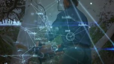 Orman kenarlarını araştıran mavi gömlekli bir adam teknoloji ağını veri tablolarıyla örtüyor. Teknoloji, bağlantı, veri, yenilik, açık hava, analiz, fütüristik