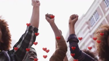 Kentsel caddede dikilen aktivistler, eylemcilikte yumruklarını kaldırarak yüzen kalpler gösteriyorlar. Eylemcilik, dayanışma, çeşitlilik, güçlendirme, birlik, protesto, toplum