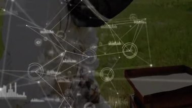 Erkek arıcı arı kovanının çerçevesini çimenli arı kovanında kaldırıyor, teknoloji düğümleri sergiliyor, bar çizelgesi örtüyor. Tarım, yenilik, araştırma, açık hava, modern, sürdürülebilirlik, veri görselleştirme