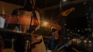 Ilık ışıklar altında müzik yapan grup arkadaşları, şehir parlaklığında mikrofon ve tıngırdayan gitarlara şarkı söylüyorlar. Konser, gece hayatı, performans, müzisyenler, sahne, eğlence, ortam