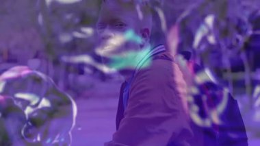 Adam şehir parkında yürüyor, pazarlama için yüzen sabun köpüğü grafikleriyle etkileşime geçiyor. Neşe, kaprisli, enerjik, dinginlik, rahatlık, yansıma, kentsel