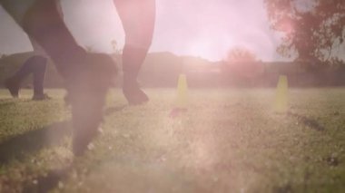 Futbol takımı gün batımında sahada külahlar arasında zikzak çizerek hız ölçümlerini gösteriyor. Sporcular, antrenman, açık hava, canlı, takım çalışması, eğlence, performans