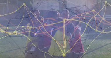 Futbol takım arkadaşları sahada kucaklaşıyorlar, parlayan spor teknolojisi verilerini ve gol ağını gösteriyorlar. Atletizm, takım çalışması, yoldaşlık, gençlik, neşe, canlılık, dijital