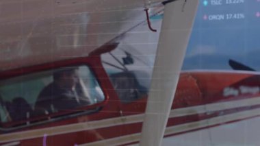 Pilot kırmızı beyaz uçağın kokpitinde oturuyor, borsa şebekesi ve çizelgeleri gösteriyor. Havacılık, finans, teknoloji, macera, navigasyon, yenilik, geri sayım