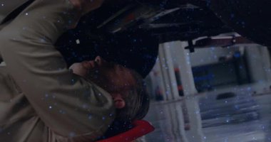 Erkek tamirci arabanın altında uzanıyor. Araba tamirinde şasiyi inceliyor. Yüzen mavi kaplamayla. Otomotiv, endüstriyel, onarım, makineler, araçlar, atölye, meslek