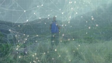 Otlak yamaçta duran yürüyüşçü, teknoloji tanıtımında dijital ağ ile etkileşime geçiyor. Macera, keşif, bağlantı, yenilik, vahşi doğa, açık hava, teknoloji