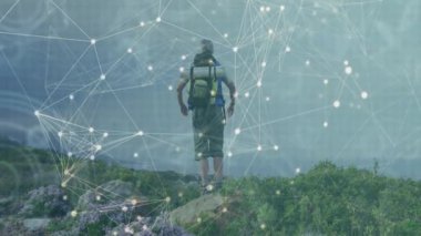 Sırt çantalı gezgin kayalık sahilde duruyor sisli denize bakıyor, ışıldayan teknolojiyi gösteriyor. Macera, keşif, vahşi doğa, bağlantı, yalnızlık, manzara, açık hava.