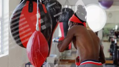 Üstsüz bir adam spor salonunda ağır torba yumrukluyor. Aynanın üzerinde hareketli sağlık ölçüleri çizelgesi var. Boks, spor, spor, spor, antrenman, motivasyon.