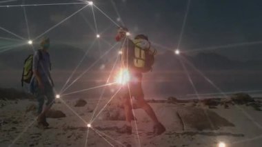 Karanlık gökyüzünün altında sırt çantalarını birbirine bağlayan teknolojiyle parıldayan bir çift kayalık sahil şeridinde yürüyüş yapıyor. Macera, açık hava, keşif, engebeli doğa, çevre, keşif