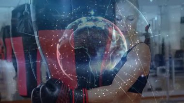 Spor salonunda boks çantasıyla kadın boksör eğitimi. Dijital grafikler ve küreyle fitness verilerini gösteriyor. Sporcu, fitness, digital, technology, sport, strength, training