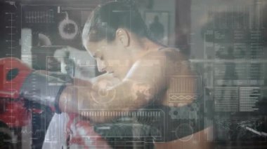 Kadın boksör spor salonunda kırmızı kum torbasına yaslanıyor ve yüzen sağlık ölçümleri gösteriyor. Sporcu, spor, güç, kararlılık, enerji, eğitim