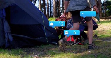 Orman temizleme alanında mavi çadırın yanında sosyal pazarlama ölçümleri gösteren üç kampçı var. Macera, açık hava, keşif, doğa, yoldaşlık, kırsal yaşam tarzı.