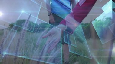 Yetişkin çiftler çayırda yürüyüş yapıyor, açık hava teknolojilerini mavi şekilli ve ışıklı gösteriyorlar. Macera, keşif, canlılık, manzara, kırsal, yenilik, refah