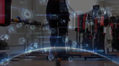 Spor salonunda atlama halatı egzersizi yapan bayan sporcu kum torbasıyla, holografik veri tablolarıyla. Fitness, training, technology, wellness, cardio, gym, active
