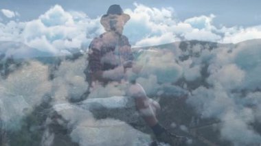 Dağ çıkıntısında harita inceleyen bir adam, hareketli bulutlar ve seyahat için en uç noktadaki grafikler. Macera, keşif, seyahat şehveti, manzara, seyahat, manzara, açık hava.