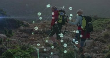 Dağda yürüyüş yapan çiftler, kayalık araziyi kaplayan para birimi ve hediye ikonları gösteriyorlar. Macera, keşif, açık hava, fitness, teknoloji, bağlantı, dayanıklılık