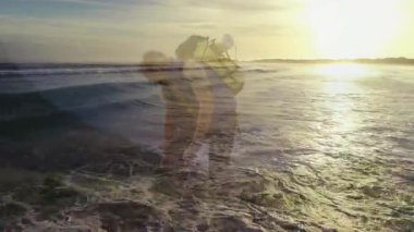 Erkek yürüyüşçü gün batımında çakıl taşı plajında diz çöküp sağlık için kalp atış hızı grafiğini gösteriyor. Macera, keşif, dinginlik, vahşi doğa, açık hava, sükunet, seyahat