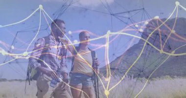 Dağ çayırlarında yürüyüş yapan iki yürüyüşçü yüzen teknoloji ağ veri grafiklerini gösteriyor. Macera, keşif, bağlantı, açık hava, teknoloji, manzara, takım çalışması