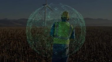 Tarım arazilerindeki tarım verilerini izleyen bir adam. Dijital ağ küresi rüzgar türbininin yanında yer alıyor. Teknoloji, bağlantı, kırsal, yenilik, sürdürülebilirlik, esneklik, manzara