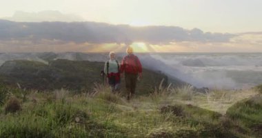 Sahil şeridi boyunca yürüyüş yapan, bot giyen, animasyon sağlık çizelgeleri ve harita kaplaması gösteren bir çift. Macera, keşif, açık hava, manzara, doğa, sağlık, aktif