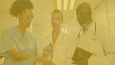 Hastane koridorundaki tablet üzerindeki verileri inceleyen tıbbi ekip canlandırılmış steteskop ikonu gösteriyor. Sağlık, işbirliği, profesyonellik, teknoloji, hastane, takım çalışması, klinik