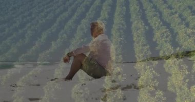 Kıdemli adam kumlu sahilde meditasyon yapıyor, dalga dalga, sağlık teknolojisinde altın desenler gösteriyor. Dinginlik, tefekkür, sükunet, doğal, ufuk, yansıtıcı, boş zaman