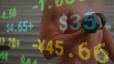 Tişörtsüz bir adam endüstriyel spor salonunda dambıl kıvırıyor, canlı stok verilerini örtüyor. Kas, güç, finans, dijital, sanayi, fitness, teknoloji