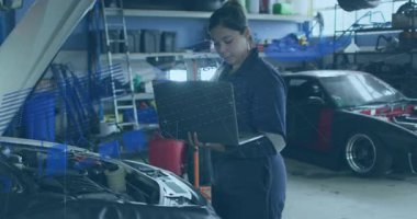 Otomotiv atölyesindeki dizüstü bilgisayarları inceleyen mekanik, motor bölmesi şemalarını gösteriyor. Otomotiv, onarım, teknoloji, sanayi, çalışma alanı, yenilik, verimlilik