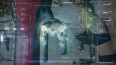 Kadın boksör, spor salonunda kum torbasını yumrukluyor. Fitness teknisyeni HUD veri örtülerini gösteriyor. Atletik, fütüristik, güç, kararlılık, şehir, eğitim, teknoloji