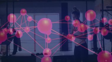 Spor partnerleri spor salonundaki dambılları ayarlıyor, neon şebeke düğümleri havada yüzüyor. Güç, işbirliği, modern, teknoloji, canlılık, eğitim, kentsel