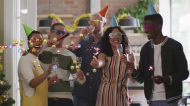 Arkadaşları parti şapkası takmış ellerinde şampanya ve mutfak pazarlama videosunda emojileri gösteren maytaplar tutuyorlardı. Kutlama, şenlik, neşe, sosyal toplantı, modern iç mekan, parti aksesuarları, tatil ruhu.