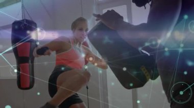 Spor salonu antrenörü ve stajyer, spor salonunda çantasıyla boks antrenmanı yapıyor. Dijital ağı örtüyor. Eğitim, spor, güç, motivasyon, atletizm, egzersiz, teknoloji