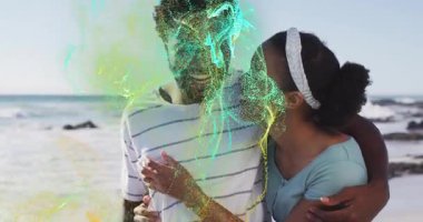 Kumlu kumsalda kucaklaşan erkek ve kadın, dönen dijital parçacıklar sergilenen teknoloji. Romantik, şefkat, samimiyet, dijital, fütüristik, canlı, kutlama