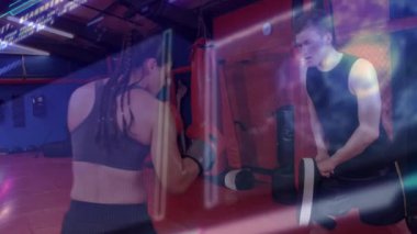 Odak eldiveni tutan kadın antrenör boks salonunda genç bir çocuğa antrenörlük yapıyor, çantalarında neon çizgileri var. Boks, antrenman, fitness, spor, spor, spor salonu, güç, kararlılık