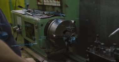 Erkek teknisyen atölyedeki torna kontrollerini ayarlıyor, holografik kodları, dünya haritası simgelerini örtüyor. Sanayi, makine, dijital, teknoloji, atölye, otomasyon, mühendislik