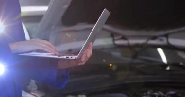 Otomotiv atölyesinde dizüstü bilgisayarda çalışan kadın tamirci. Motor bölümünün üzerinde animasyon veri grafikleri var. Otomotiv, endüstriyel, modern, hassas, teknolojik, profesyonel, temiz